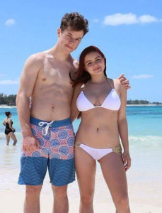 Nolan Gould shirtless on the beach with his co-star from Modern Family Ariel Winter wearing a white bikini