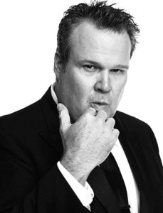 Great black and white photo of Eric Stonestreet in a suit with the hand in his chin