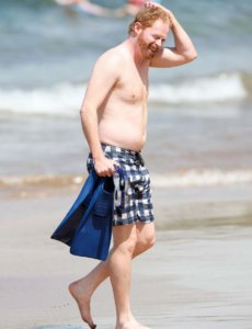 Jesse Tyler Ferguson shirtless on the beach scratching his head