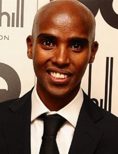 Mo Farah smiling in a black suit and tie