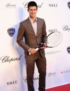 Novak Djokovic in a brown suit with a tennis racket in his hand