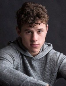 Nolan Gould in a photo session wearing a gray sweater